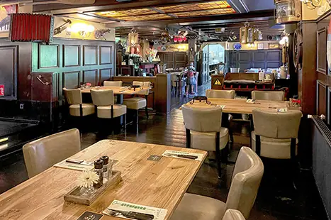 Zaal met rode bankjes en de bar op de achtergrond
