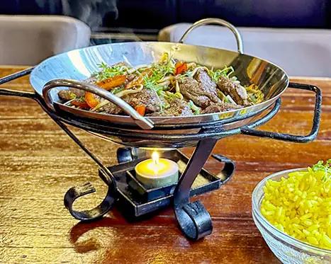 Wokpan met ossenhaaspuntjes en groenten op een standaard
